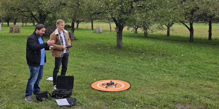 Mitarbeiter der PH Heidelberg mit einer Drohne im Apfelgarten