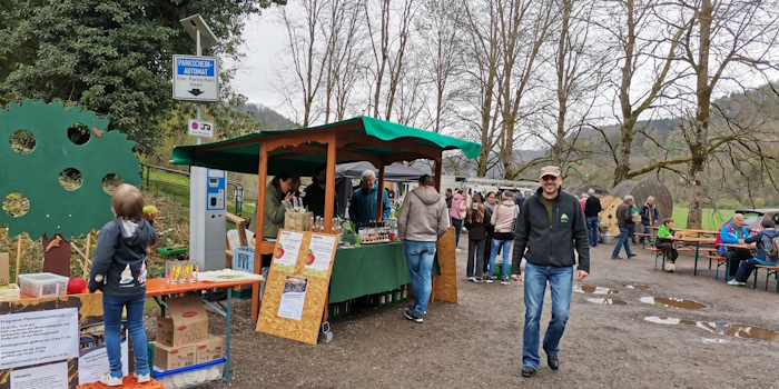 Marktstand mit regionalen Produkten und Besuchern